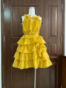 Détail d'une robe licou en mousseline jaune à volants superposés sur un mannequin blanc