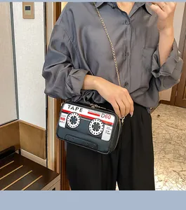 Unique and quirky retro cassette tape crossbody bag with gold chain strap shown on model