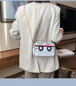 Creative cassette tape shaped crossbody bag with gold chain strap on white blazer