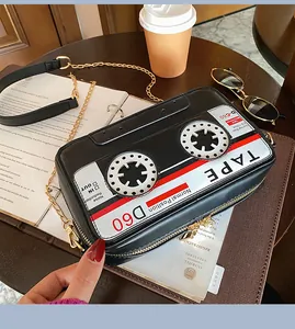 Close-up detail of a creative black cassette tape shaped crossbody bag with gold chain