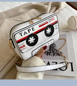 Close-up detail of retro white cassette tape shaped handbag with chain strap.