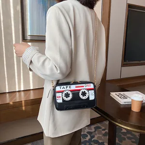 Detailed side view of a creative cassette tape shaped crossbody bag with gold chain