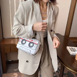 Retro cassette tape shaped crossbody bag with gold chain strap shown on fashion model