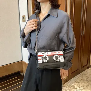 Detailed close-up of a vintage cassette tape design crossbody bag worn on a gold chain