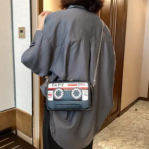 Close-up of a vintage cassette tape shaped crossbody bag with a gold chain strap on a model