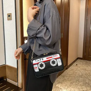 Unique quirky cassette tape shaped crossbody bag with a fashionable gold chain strap.