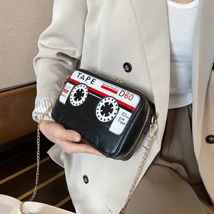 Close-up detail of a unique retro cassette tape shaped crossbody bag with a gold chain strap