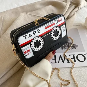 Close-up of retro black cassette tape shaped crossbody bag with gold chain strap