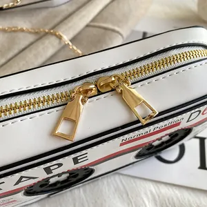 Close-up of gold dual zippers on a white cassette tape shaped crossbody bag
