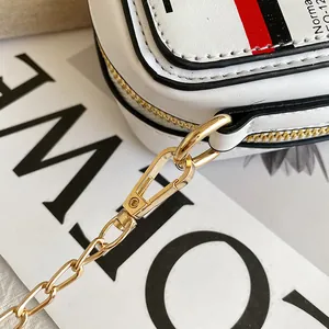 Close-up view of the polished golden chain hardware on a stylish white cassette tape crossbody bag