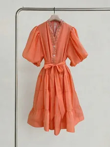 Elegante vestido naranja con mangas abullonadas, escote en V con cuentas y cinturón.