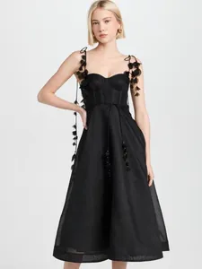Détail d'une élégante robe noire en soie et lin avec des bretelles à fleurs en 3D.
