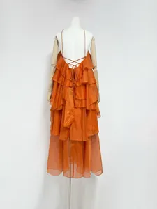 Detail view of an orange tiered ruffle backless maxi dress with cross straps.
