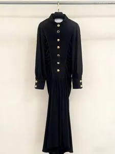 Elegant black long-sleeve dress with decorative gold buttons and pleated front detail