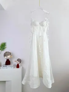 Détail de robe midi blanche en soie et lin avec bretelles pétales et lien à la taille