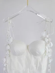 Détail d'une robe en soie et lin blanc avec bretelles ornées de pétales 3D et perles