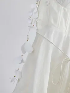 Gros plan d'une robe en soie et lin blanche avec détails de pétales et perles