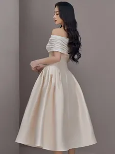 Elegante off-shoulder A-lijn avondjurk van champagne satijn met witte getextureerde top
