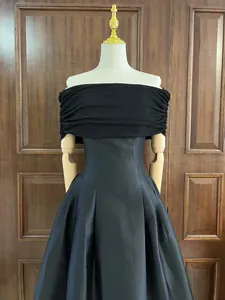 Elegante zwarte avondjurk met blote schouders, geplooid lijfje en wijde satijnen rok.