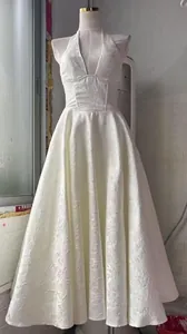 Vista detallada de vestido de noche blanco con cuello halter y textura jacquard en maniquí