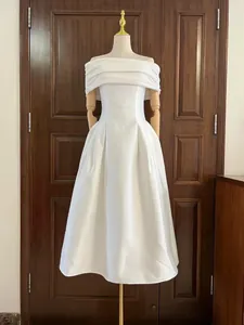 Elegante witte midi-jurk met blote schouders en een getailleerde taille op een etalagepop