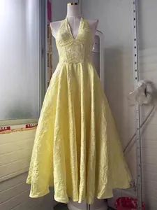 Elegante vestido maxi amarillo con cuello de pico y falda acampanada con textura