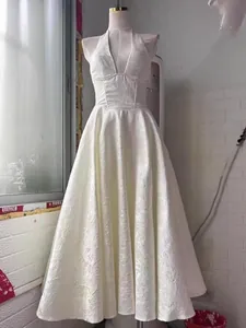 Elegante vestido de noche largo blanco con cuello halter y escote en V en un maniquí