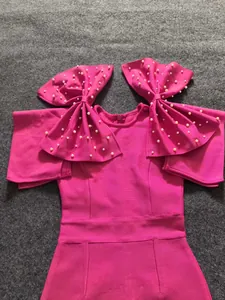 Detailed view of a fuchsia bandage dress featuring oversized pearl-studded shoulder bows.