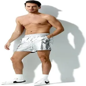 Full-body lifestyle view of a male model wearing metallic silver shiny leather shorts
