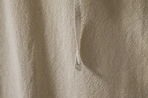 Macro shot of breathable cotton linen fabric on a beige men's hippie Henley shirt