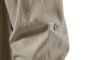 Detailed macro view of men's cotton linen shirt sleeve featuring textured fabric and button