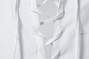Macro close-up view of lace-up drawstring detail on white cotton linen men's hippie shirt