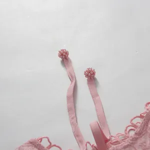 Close-up detail of pink lace dress showing drawstring with beaded berry charm accents