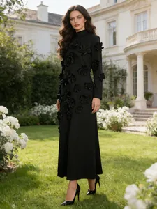 Elegant black long-sleeved dress with 3D floral appliques shown in a garden setting