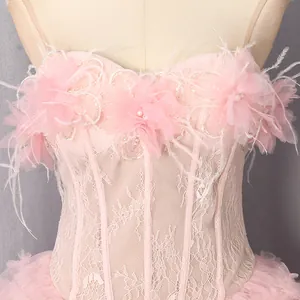 Detail van een elegante roze kanten korsetjurk met 3D-bloemapplicaties en veren