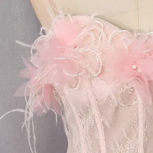 Detailopname van roze kanten jurk met delicate versieringen van veren en kralen.