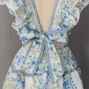 Gros plan du nœud arrière et des volants sur une robe d'été à fleurs bleues.