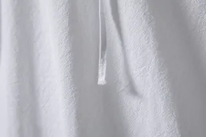 Close-up detail of breathable white cotton linen fabric texture on a men's shirt.