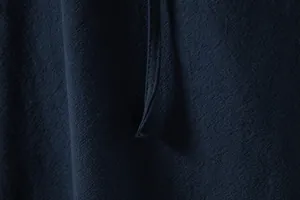 Close-up detail showing the navy blue cotton linen fabric texture and stitching of the shirt