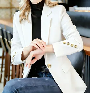 Nahaufnahme eines eleganten, weißen Slim-Fit-Blazers mit markanten goldenen Knöpfen