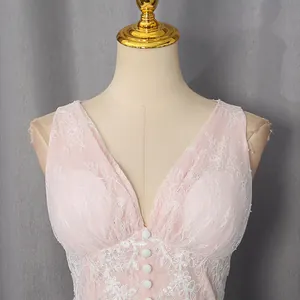 Close-up detail of an elegant pink lace dress with floral embroidery and white button accents