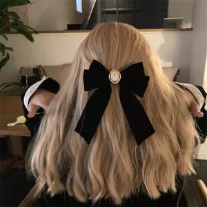 Gros plan d'un nœud en velours noir avec emblème de rose sur des cheveux blonds ondulés