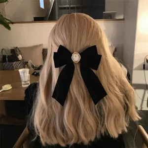 Vue détaillée d'une barrette à cheveux vintage en velours noir sur cheveux blonds.