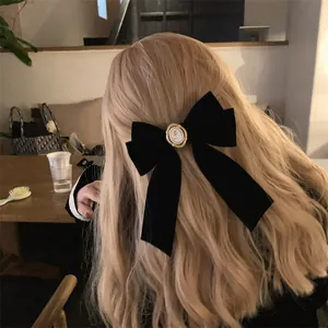 Gros plan d'une barrette à cheveux en velours noir avec nœud et détail camée vintage