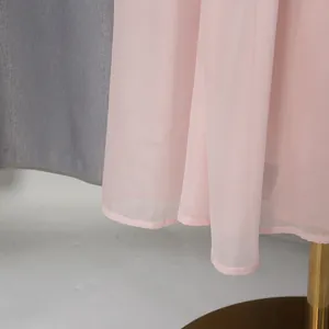 Detail macro view of elegant pink chiffon maxi dress hemline with soft fabric texture.