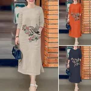 Détail de la broderie sur une robe midi ample à manches longues en trois couleurs
