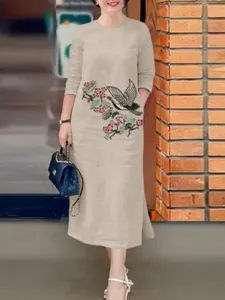 Détail d'une élégante robe longue beige avec des broderies complexes de grues et de fleurs
