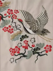 Gros plan détaillé d'une broderie de grue et de fleurs sur un tissu de robe beige