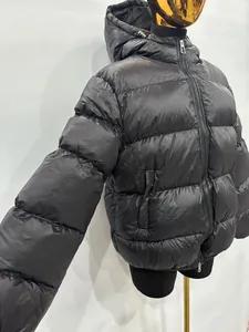 Detalle lateral de un plumífero negro con capucha y un diseño de doble cremallera