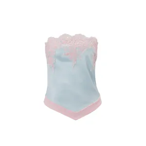 Detalle del bordado de encaje rosa y la textura satinada en el top azul claro sin tirantes.